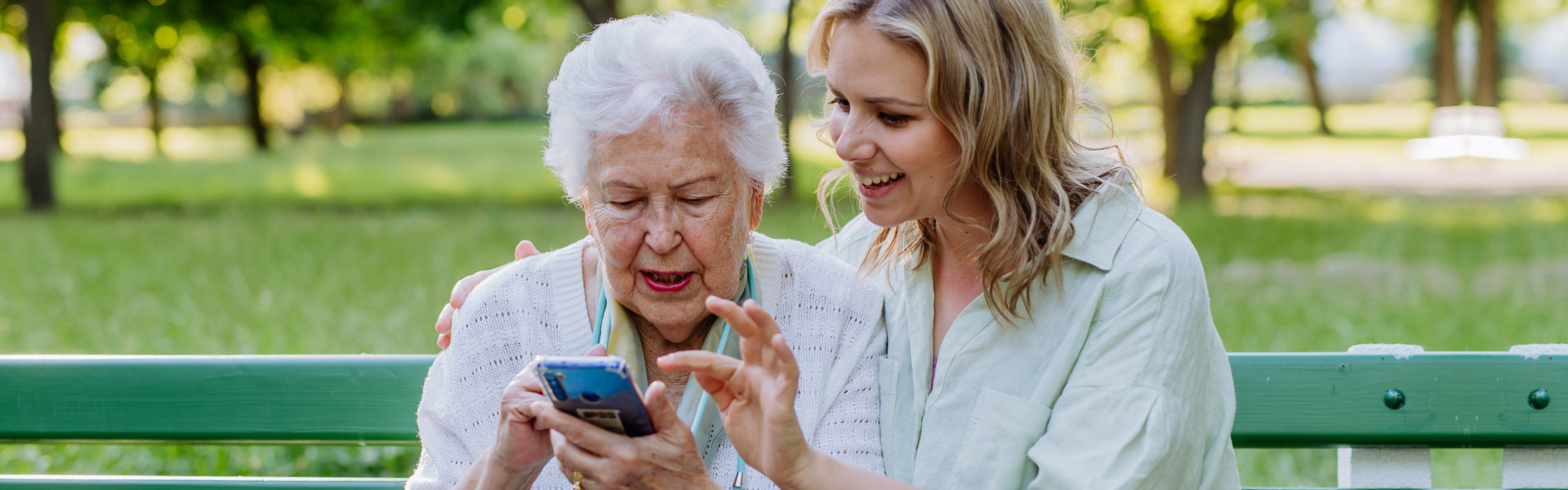 woman teaching her grandmother how to use a smartphone